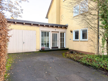 Hauseingang mit Garage und Stellplatz davor